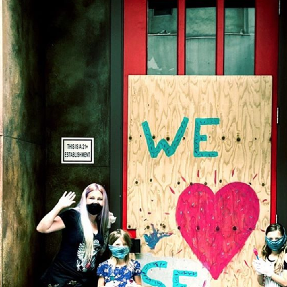 Woman in front of her business with a We love SF sign 