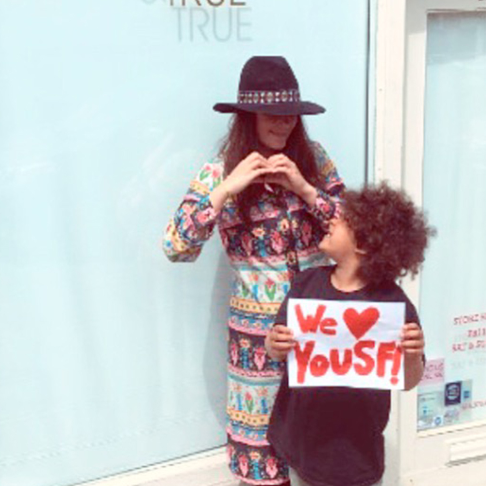 Woman and her son in front of her business with a We love SF sign 