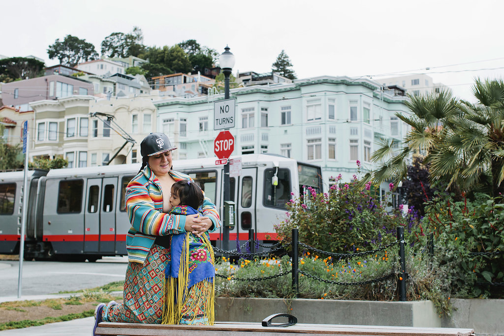 Native mother breastfeeding at Muni stop