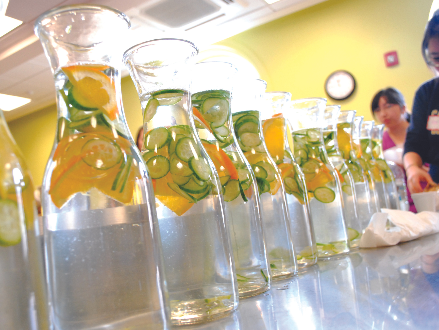 An array of water carafes on a table, each with fresh lemon and lime slices.