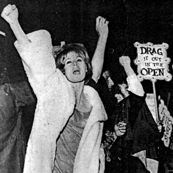 Protester in a white coat with their fist raised in the air