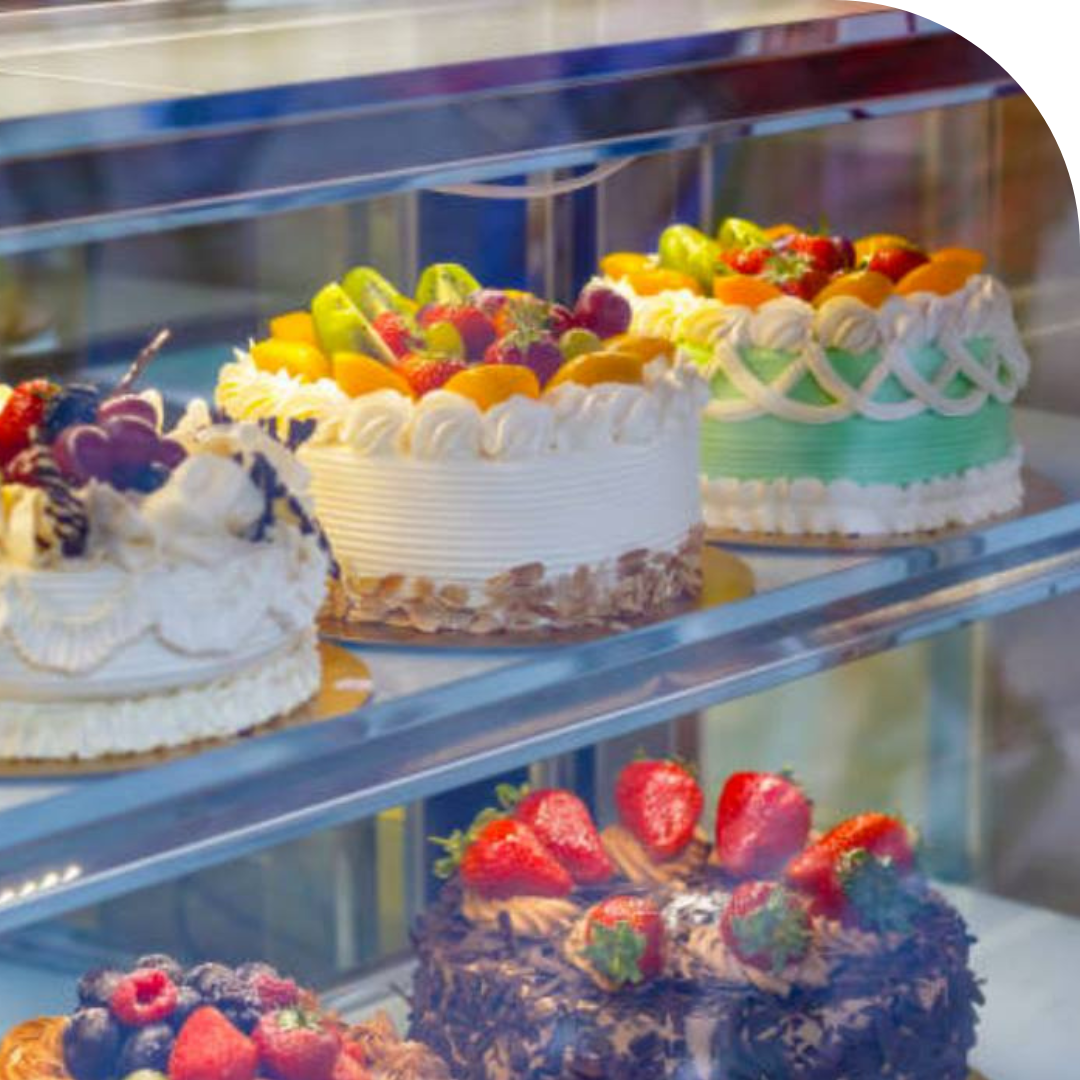 Photo of 5 decorated cakes in a glass display case