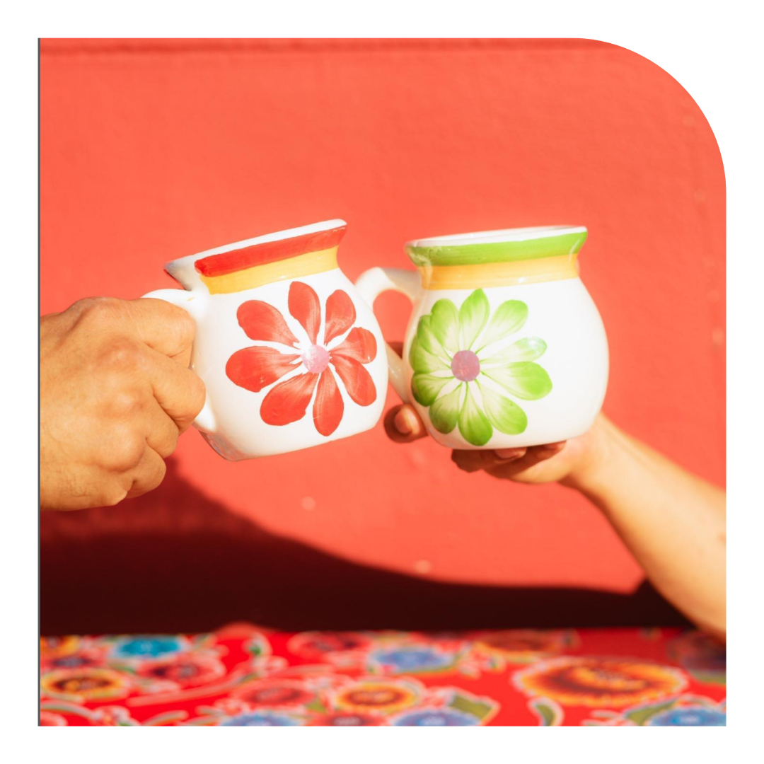 Photo of 2 mugs above a colorful tablecloth