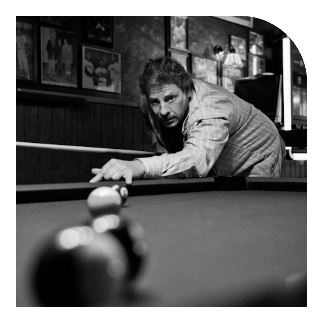 black and white photo of someone playing pool in a bar