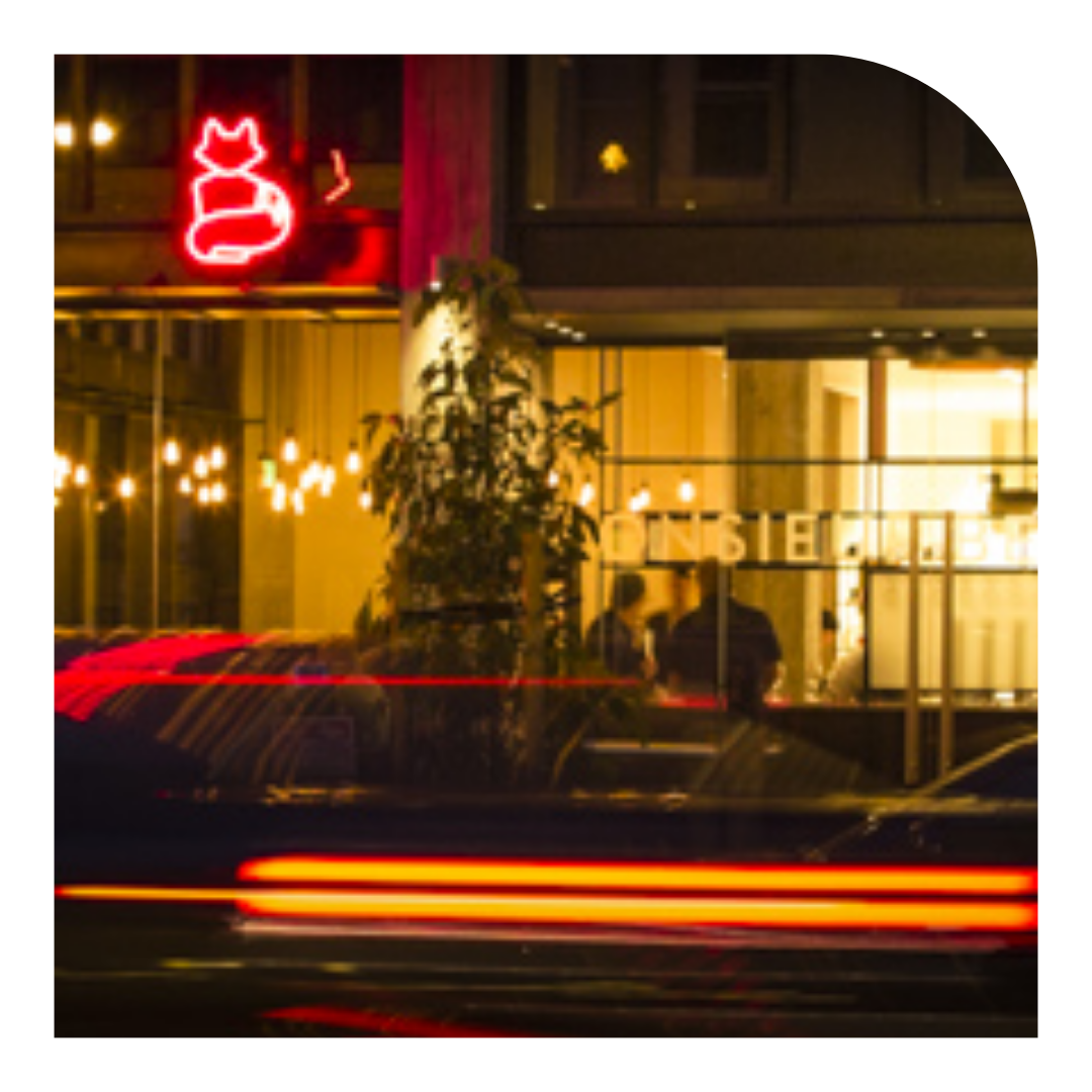 photo of a neon sign of a cat with a restaurant below