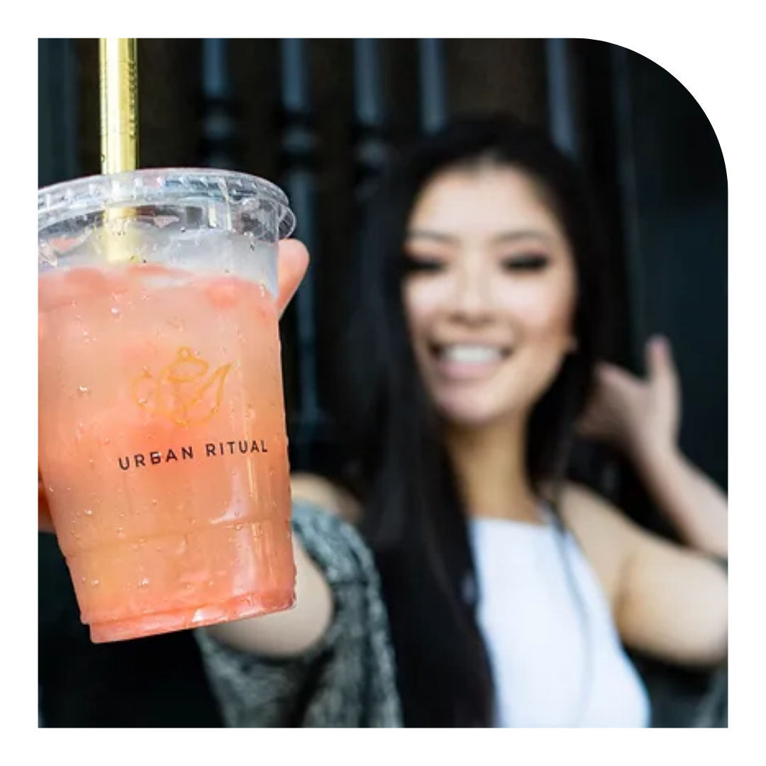 photo of a smiling person holding out a pink beverage