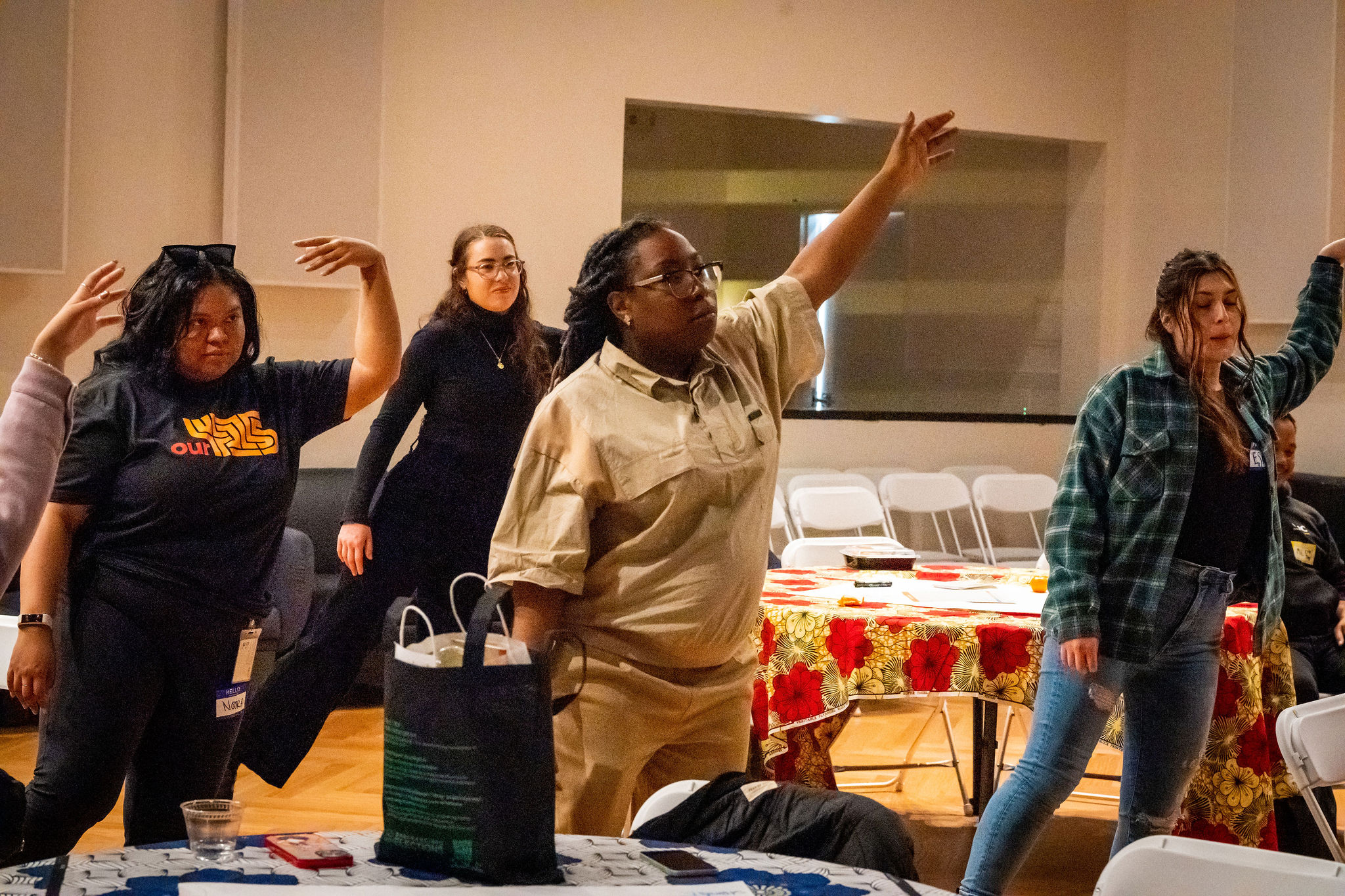 A group of people in a room doing movement excercises.