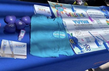 An outdoor table with a blue tablecloth featuring YUTHE promotional items