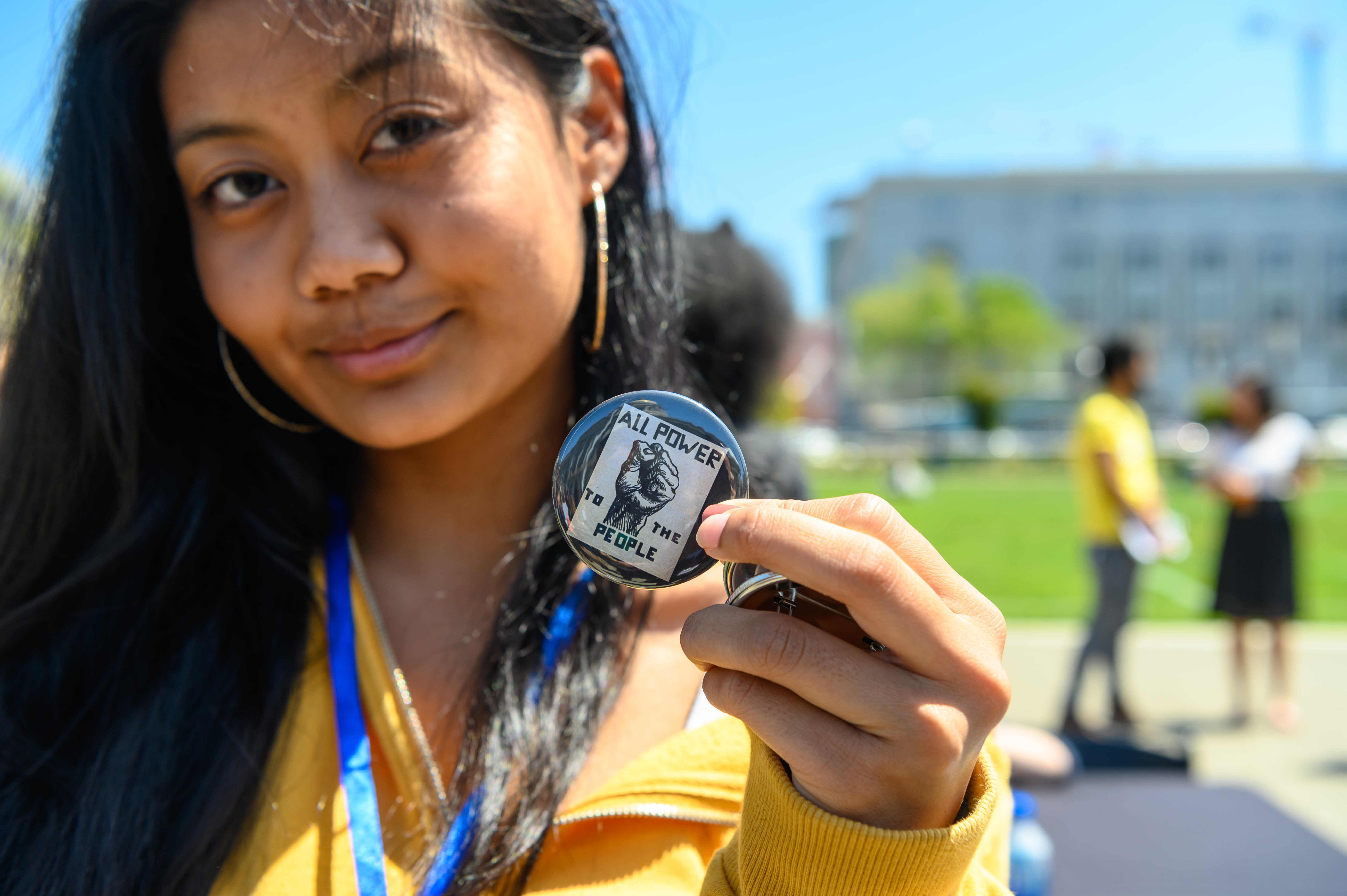 A young person holding a button with the words "power to the people"
