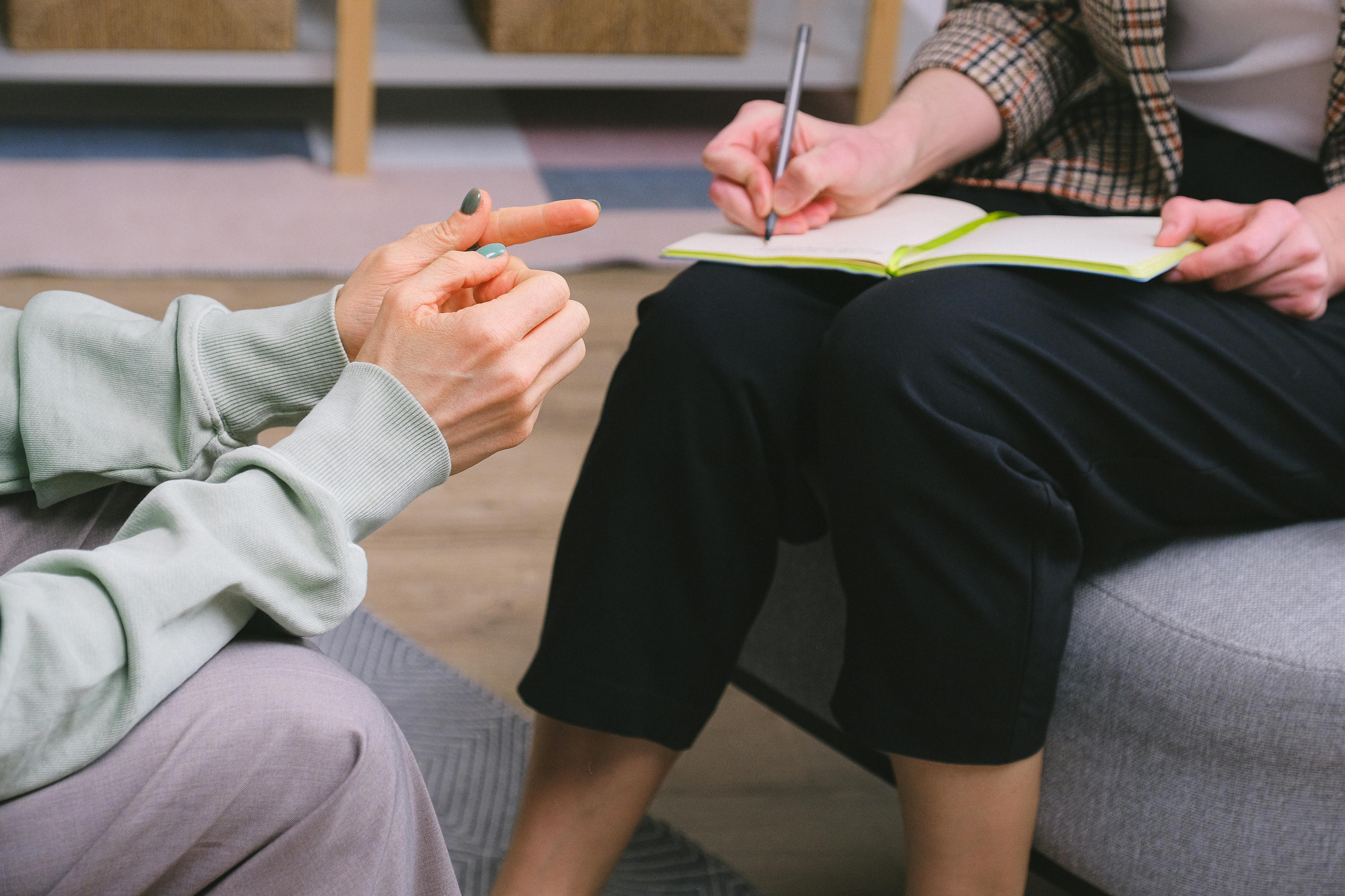 Anonymous female doctor and client sitting in armchairs during session in modern office