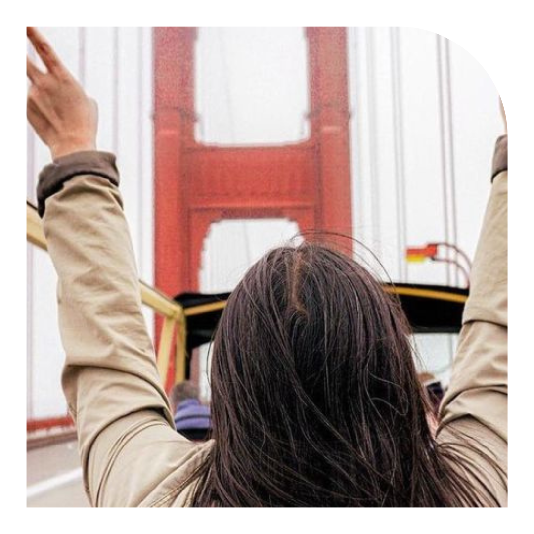 Photo of the back of a person's head, with long brown hair, looking out on the Golden Gate Bridge