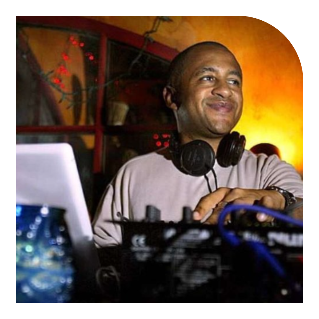 Photo of a DJ with headphones around their neck looking to side and smiling