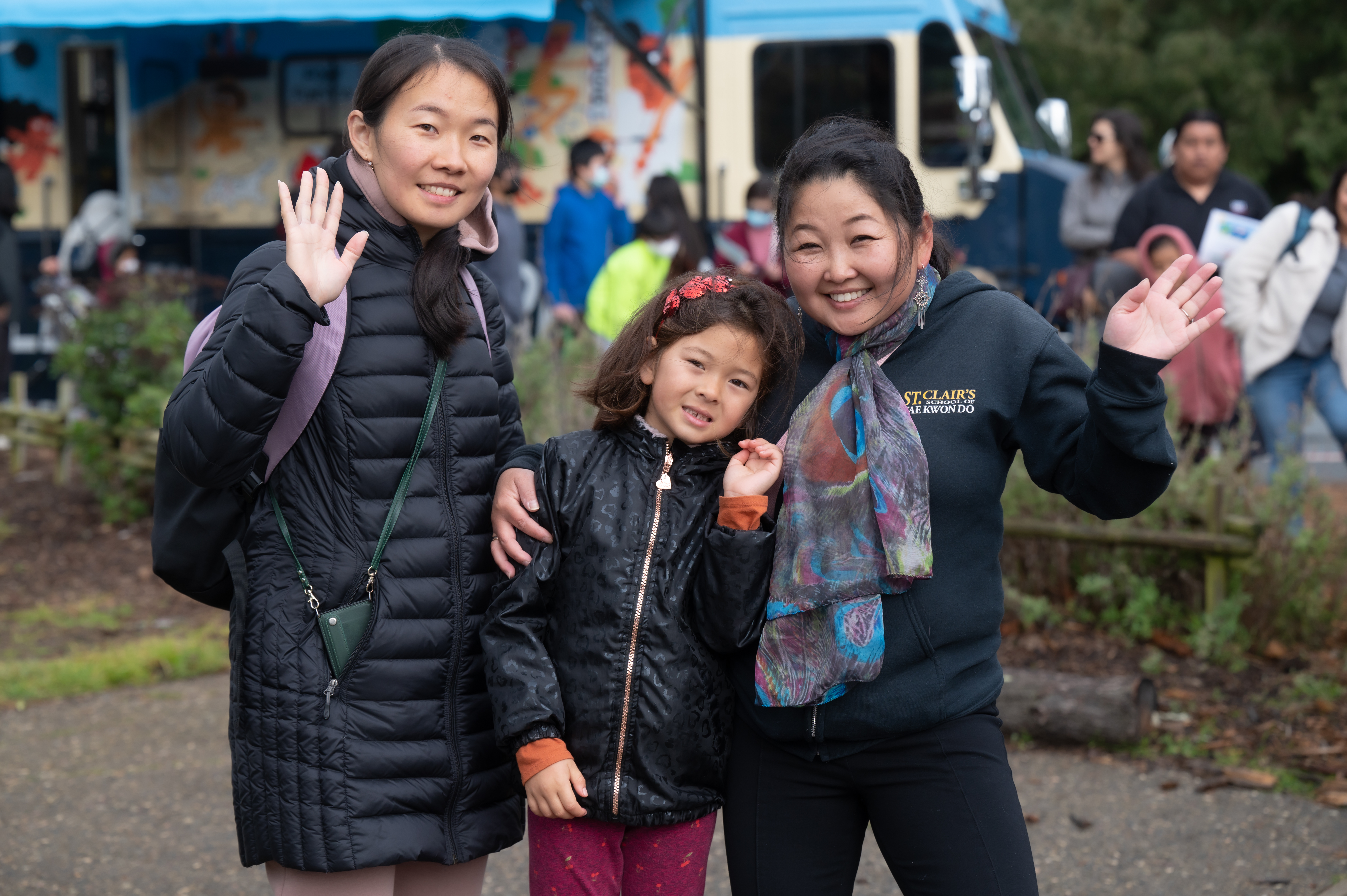 Two adults and a child smiling and waving 