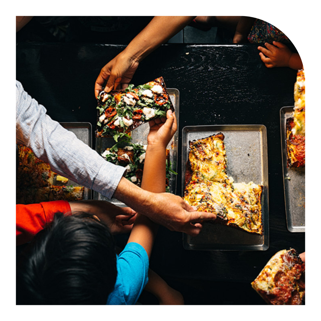 overhead photo of pizza and people eating