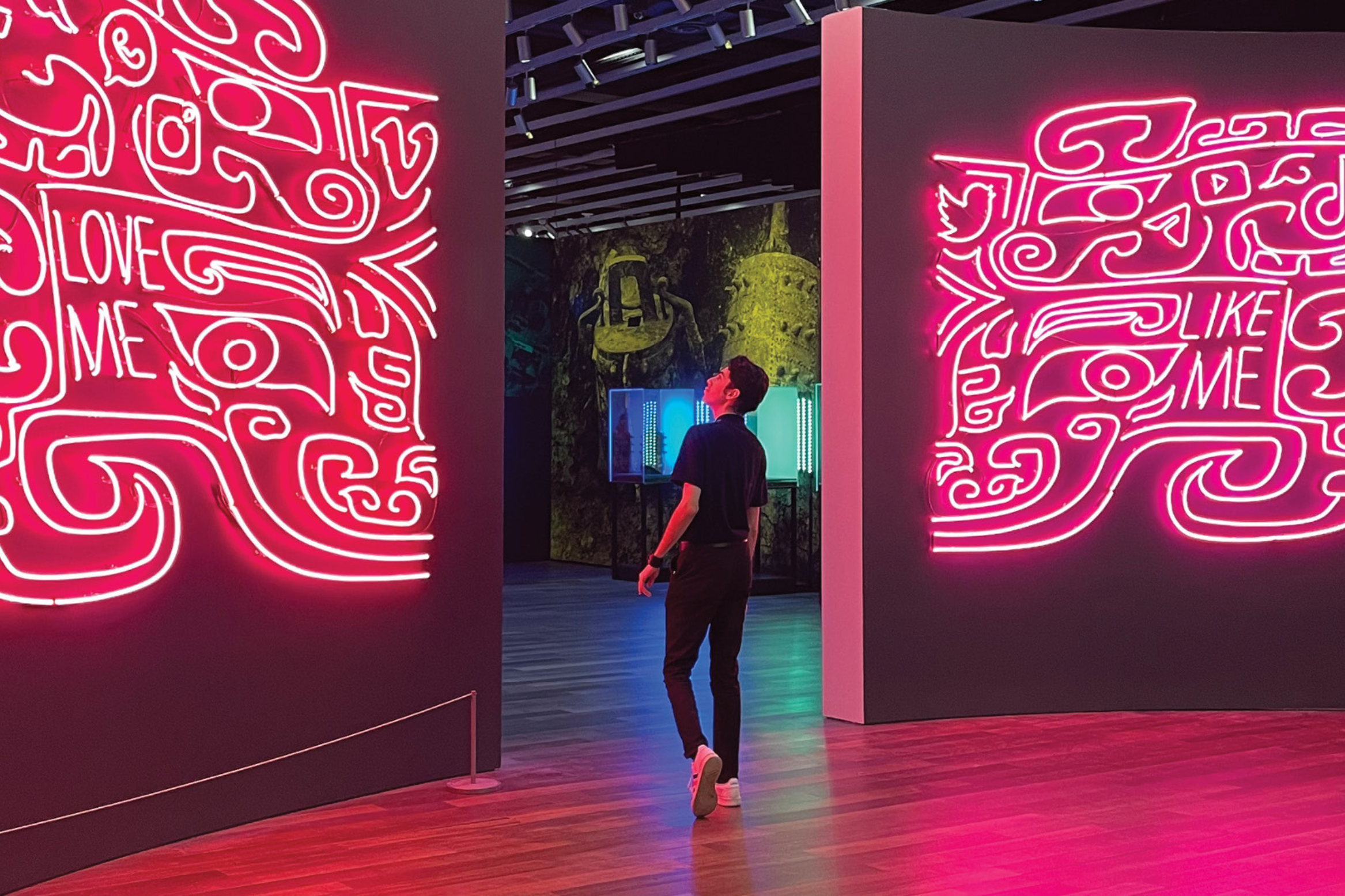 photo of a person at a museum, looking at pink neon artwork