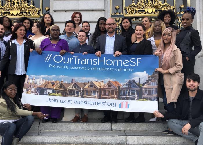 Group of people holding banner on steps of City Hall