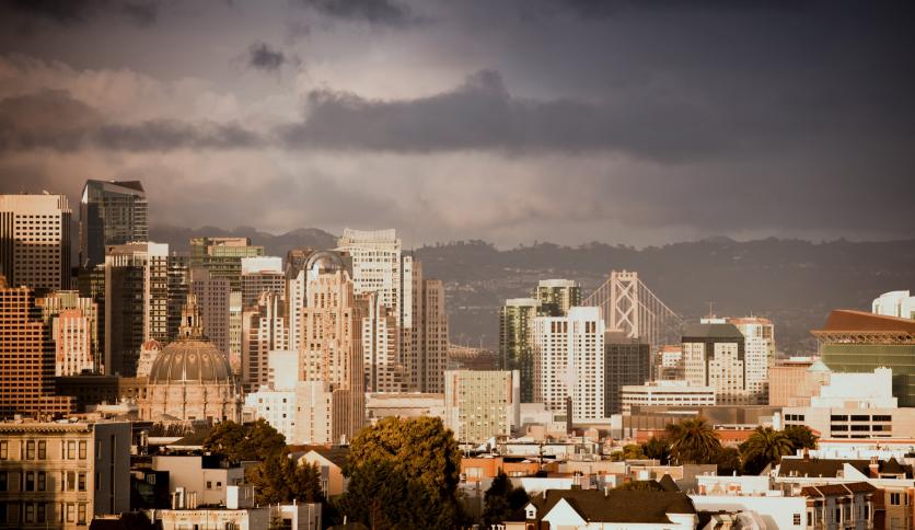 Skyscrapers and landmarks of San Francisco dwarfed by a heavy storm on the horizon. San Francisco City Hall is in the foreground.