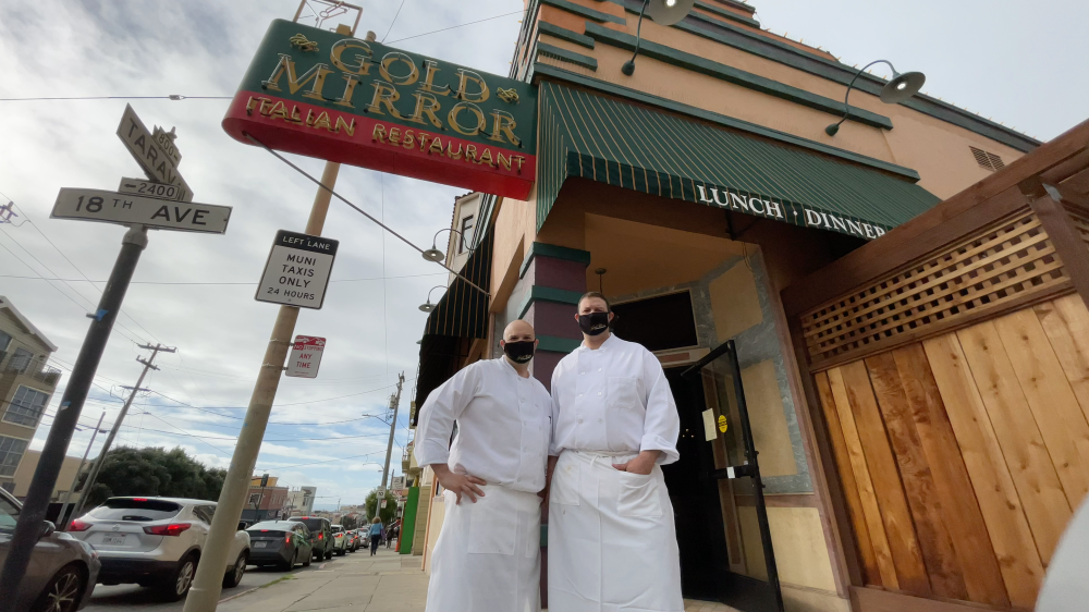 Two male restauranteurs in white outfits (Roberto Di Grande, left, and Domenico Di Grande, right) in front of Gold Mirror