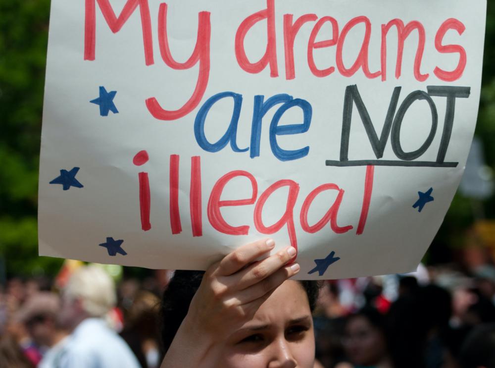 Young woman holds sign at a protest that reads "my dreams are not illegal"