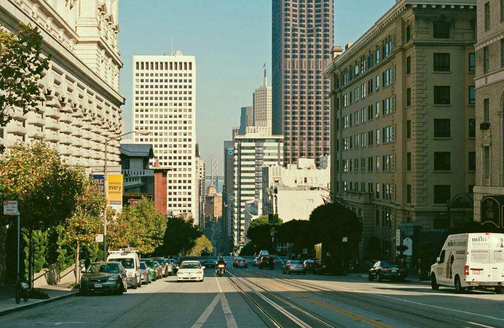 View of the middle of a street with tall buildings on both sides during the day