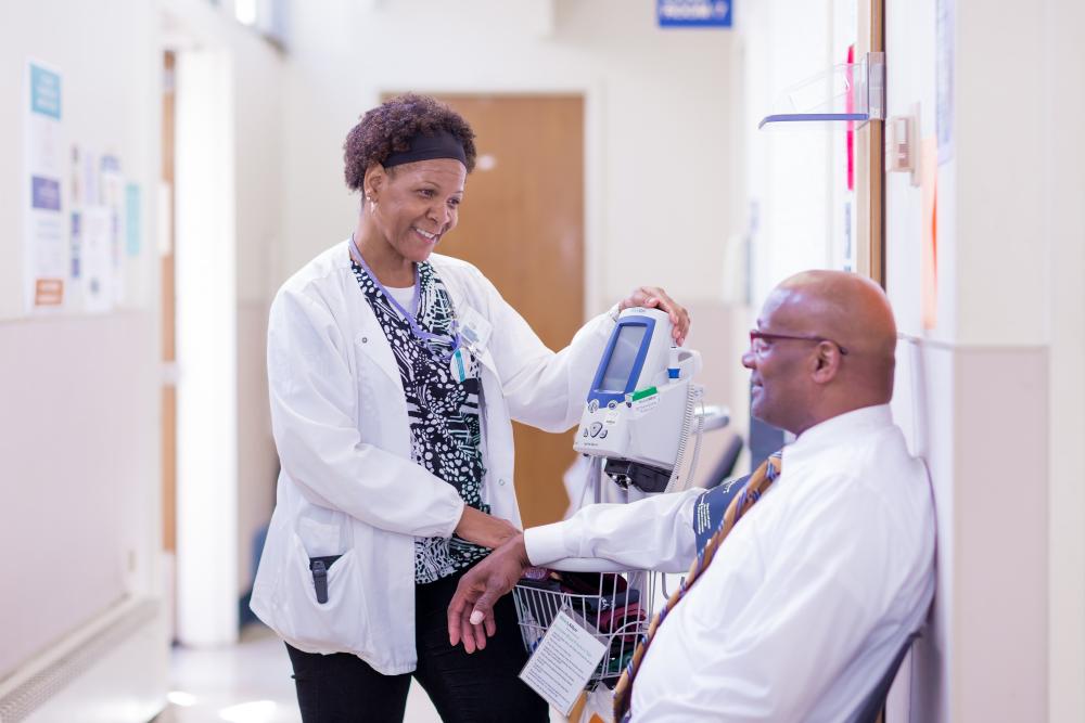 Doctor standing with sitting patient at Maxine Health Center