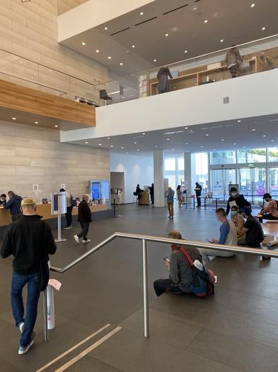 A view of the lobby of 49 South Van Ness, with customers standing and sitting around the information desk.