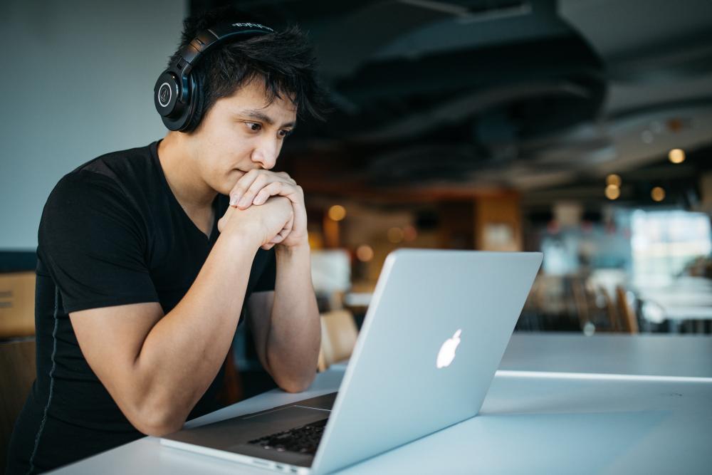 man wearing headphones while sitting on chair in front of the laptop