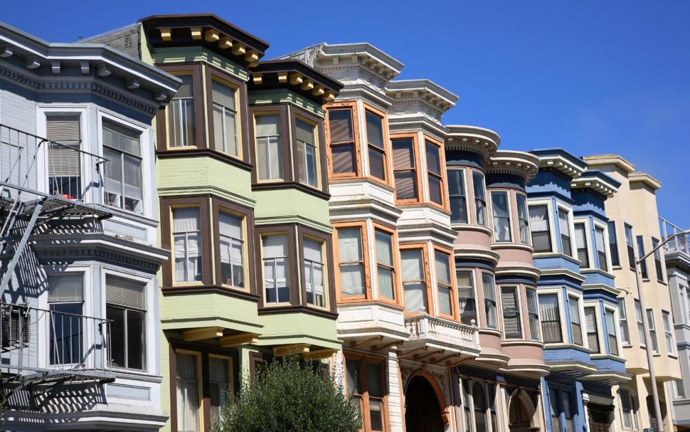 A series of multi-colored Victorian-style homes, with focus on the bay windows.