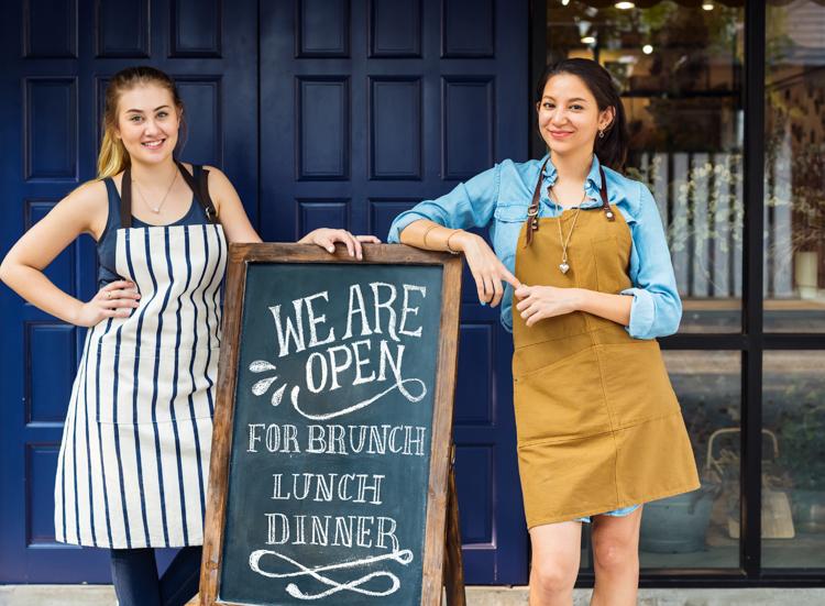 Female business owners posing in front of opening sign