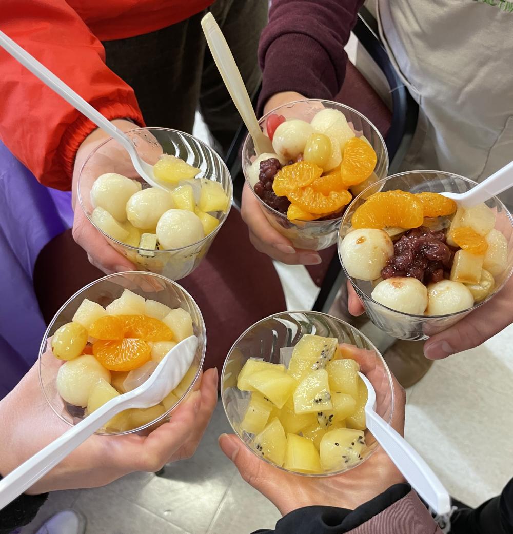 Homemade fruit cups are held out by 5 people