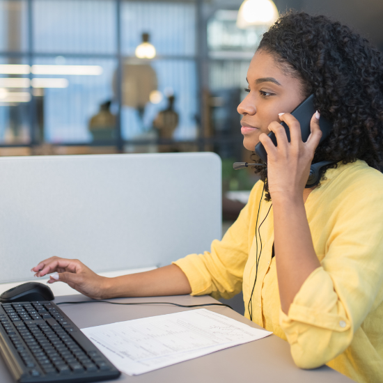 Woman sitting at a desk talking on her cell phone