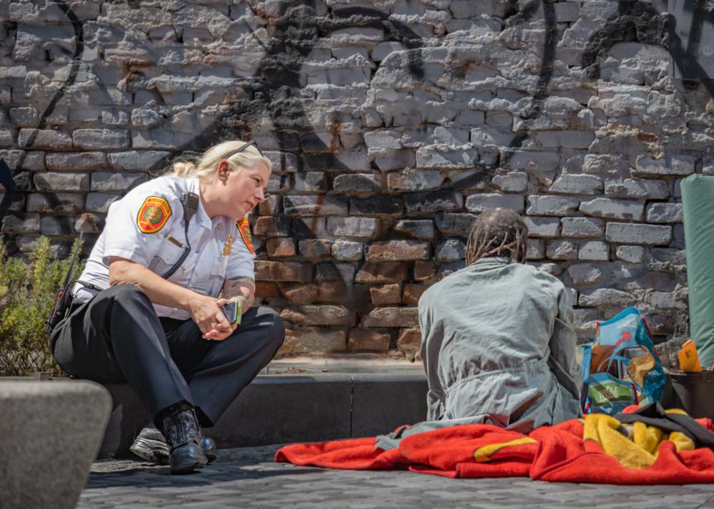 A staff member from the San Francisco Fire Department sits and speaks with a person experiencing homelessness. 