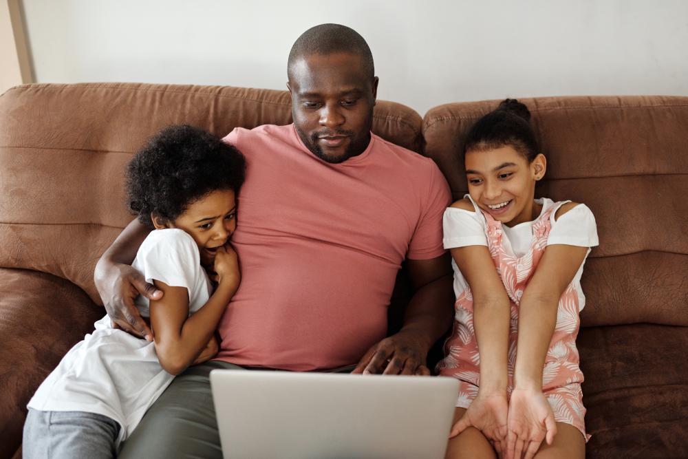 Family Sitting on a Sofa and Looking at a Laptop
