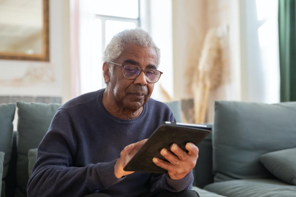 An Elderly Man in Black Sweater Using a Digital Tablet