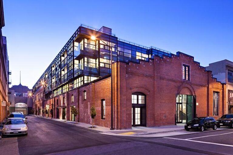 A red brick apartment building on an urban street corner. The sun is setting. 