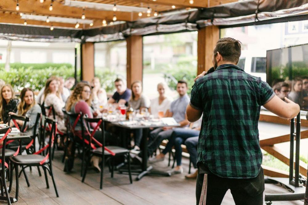 A person speaking to people sitting on tables