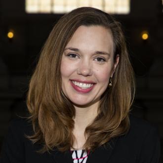 Woman with shoulder-length brown hair, wearing a black jacket.