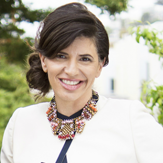 Photo of Commissioner Anne Moses who has dark brown hair, is wearing a necklace and a white top and is smiling