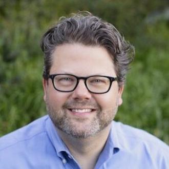 A man, smiling facing forward.