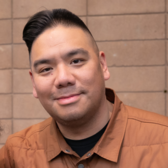 Aaron Yen smiling in front of a brown background